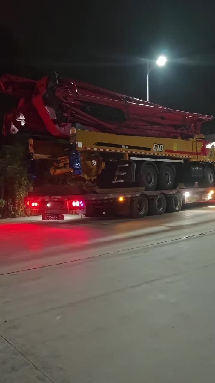 Concrete pump truck on a road transport trailer at night in an original Mechabro field video still
