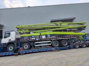 Original Mechabro field photo of a 2020 Zoomlion 56m used concrete pump truck on a low-bed trailer for a customer dispatch to Africa