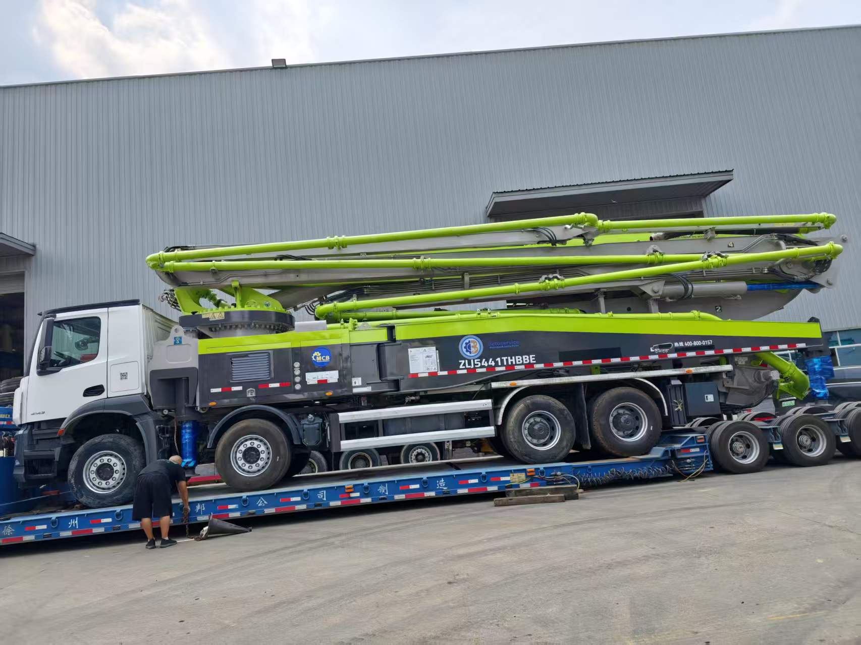 Original Mechabro field photo of a 2020 Zoomlion 56m used concrete pump truck on a low-bed trailer for a customer dispatch to Africa